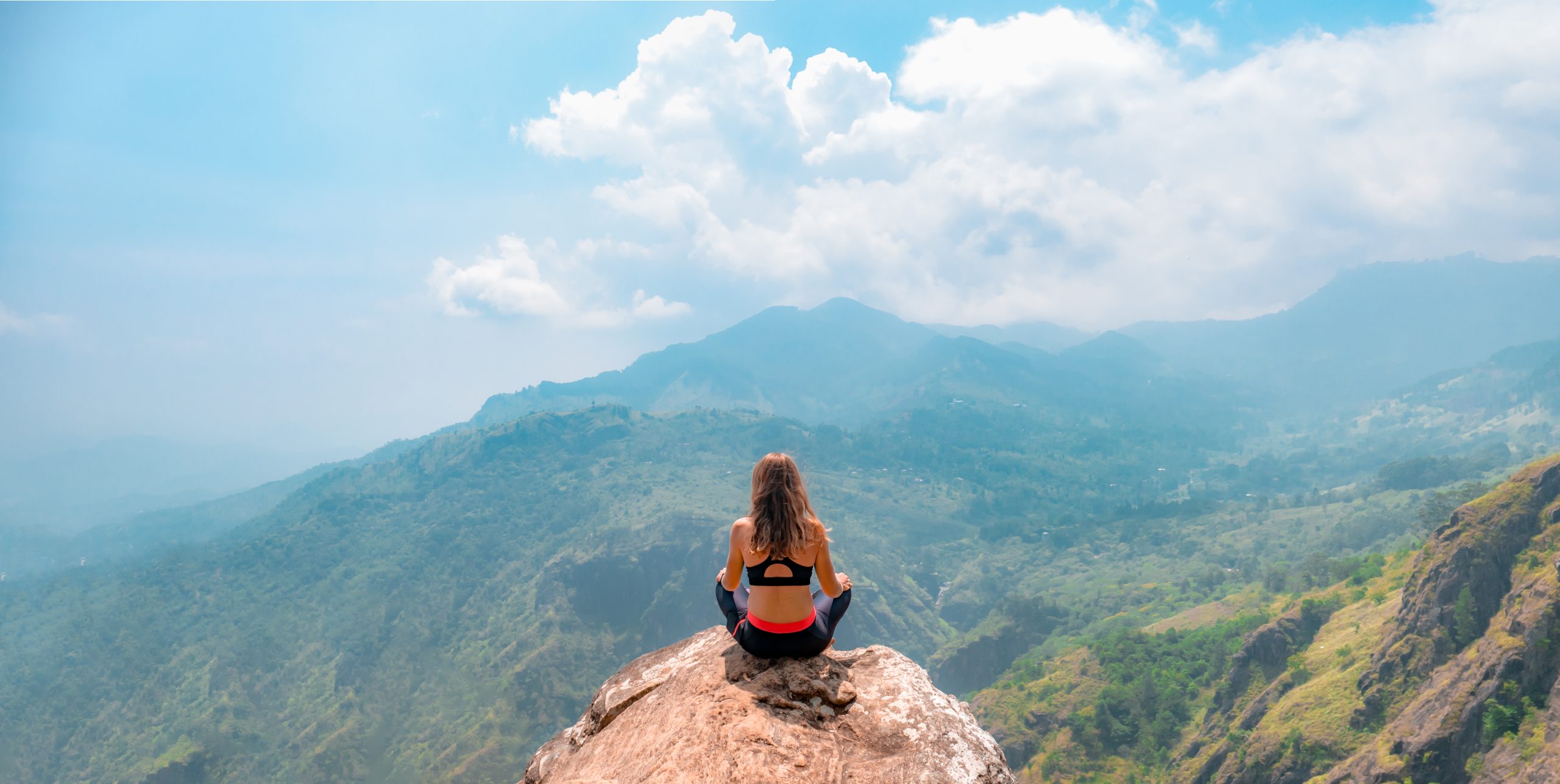 a woman doing yoga on a top of a hill