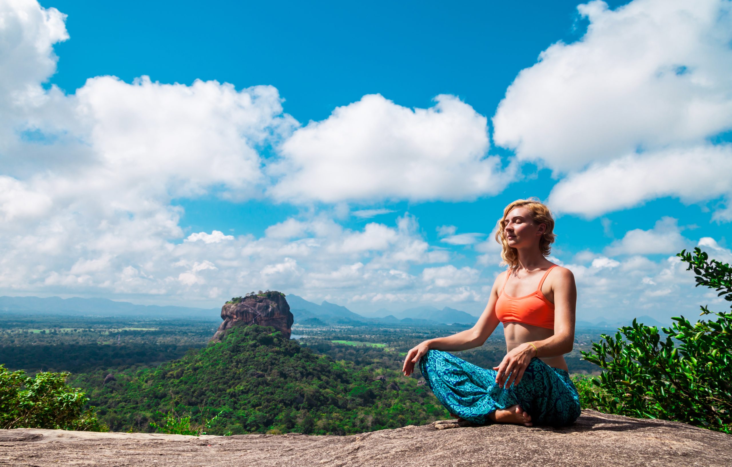 a solo female traveler meditating near Sigiriya rock